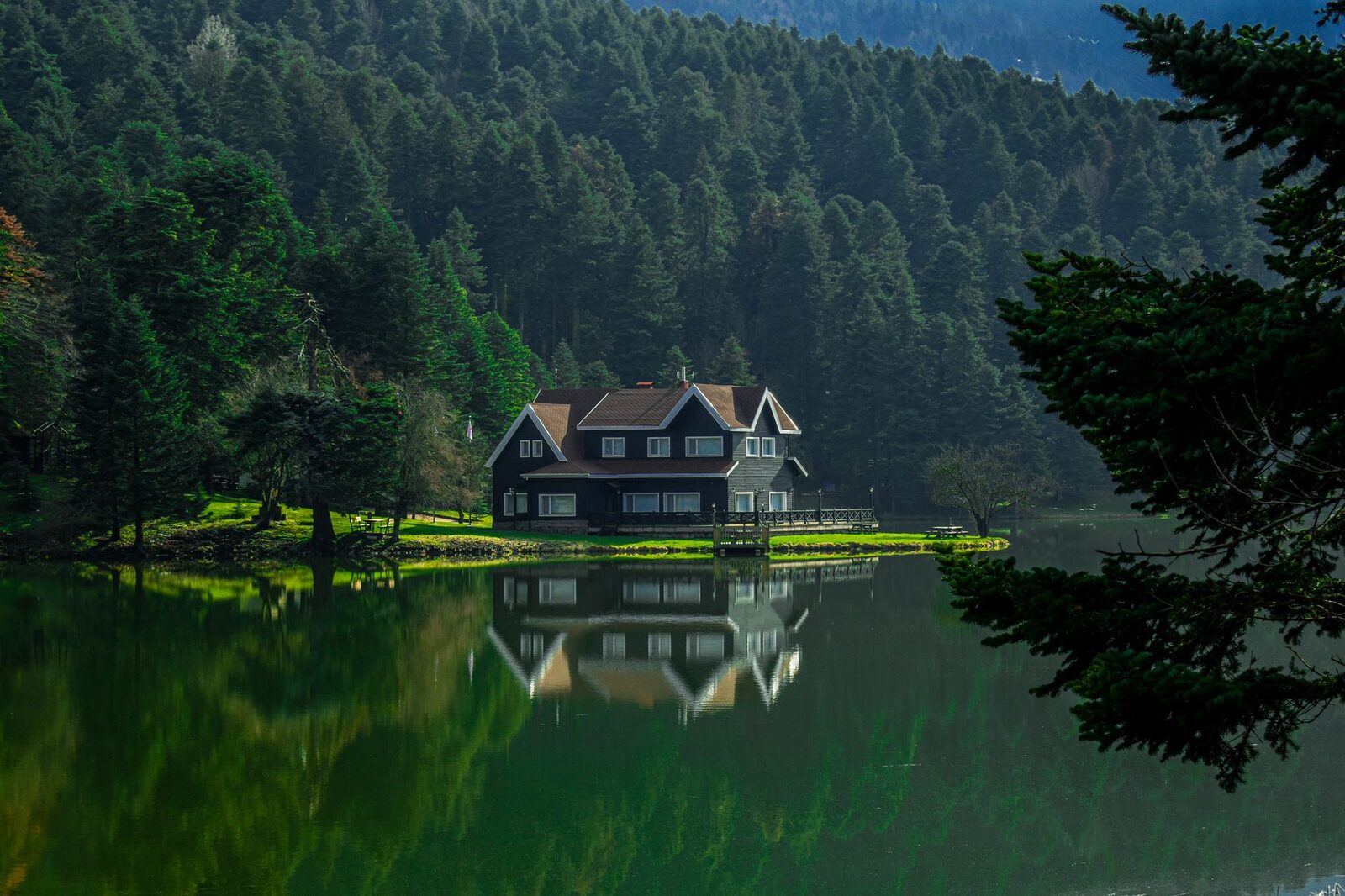 Charming lake house reflecting in water surrounded by lush forest in Gölcük Köy, Bolu.
