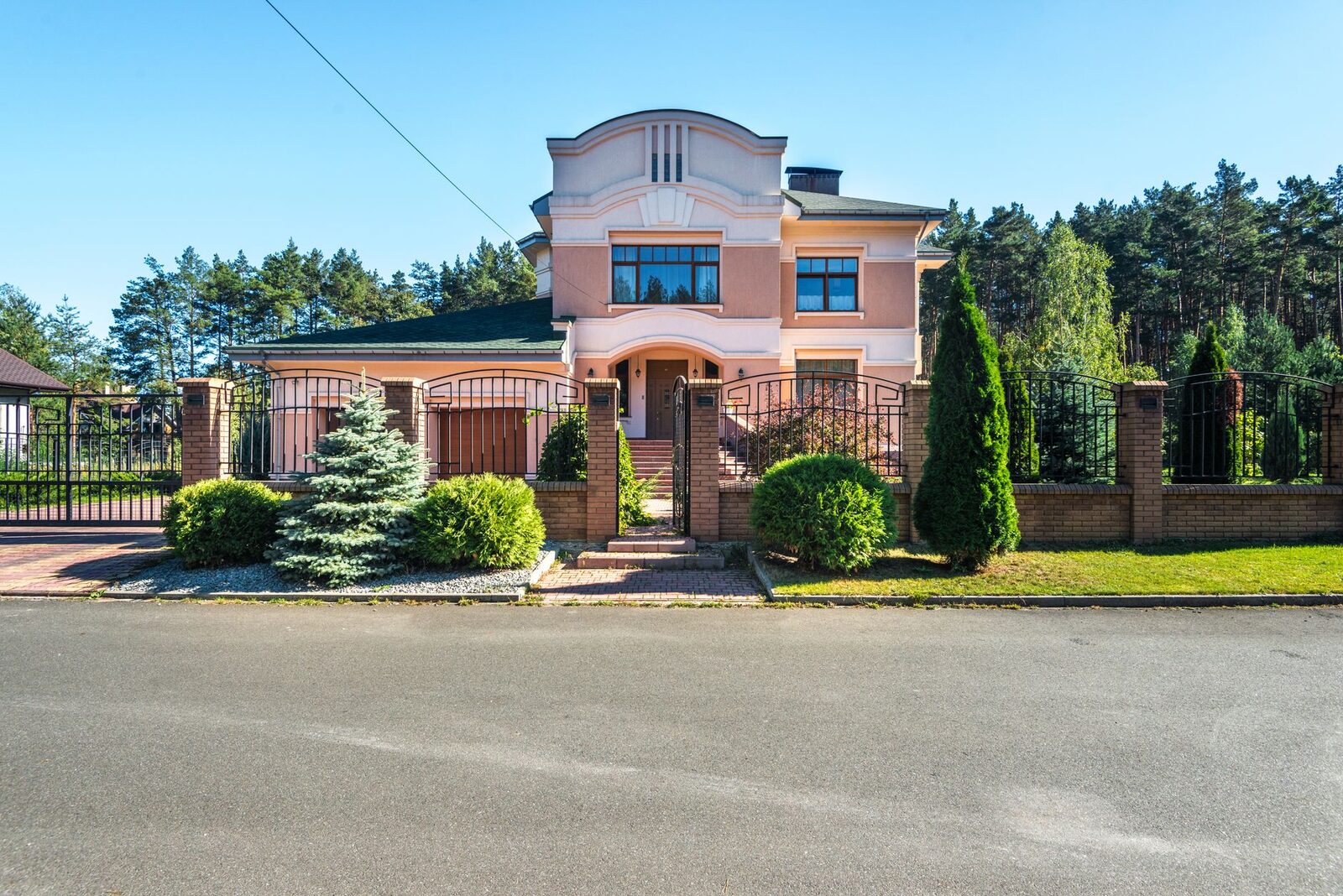 Beautiful luxury suburban house with landscaped garden and gated entrance on a sunny day.